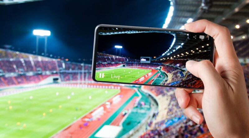Hænder bruge smartphones rekord fodbold konkurrence kamp i fodbold stadion live streaming video på internettet til sociale medier kommentar chat til ven